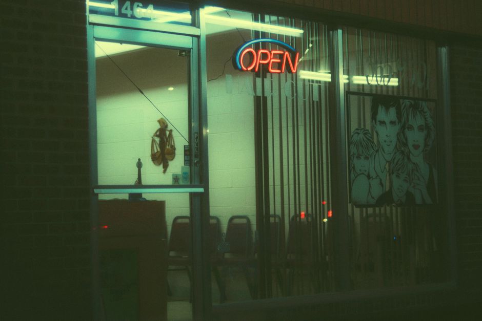 A classic barber shop with a glowing neon 'Open' sign captured at night, exuding a vintage vibe.